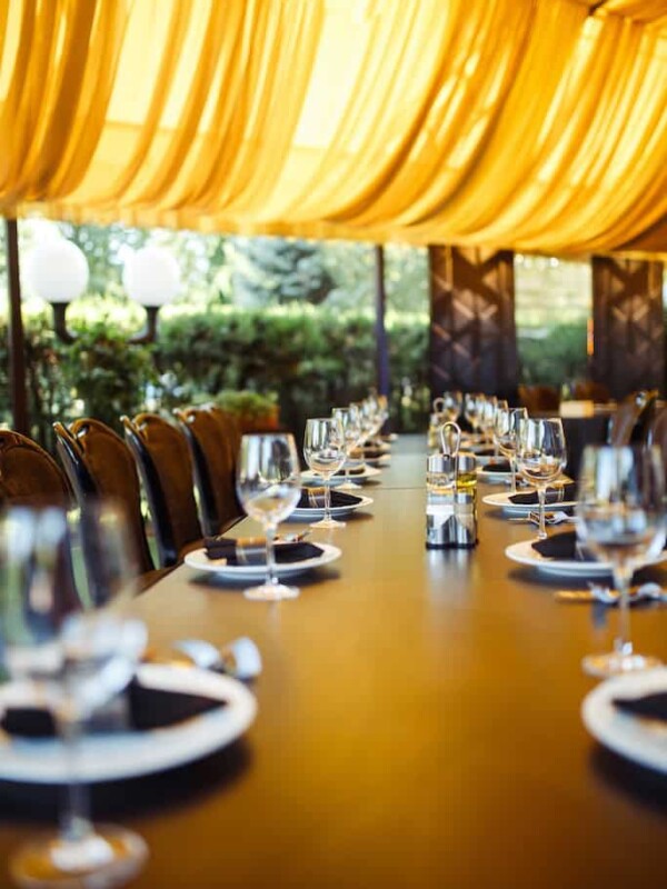 Sparkling glassware stands on long table prepared for wedding dinner.