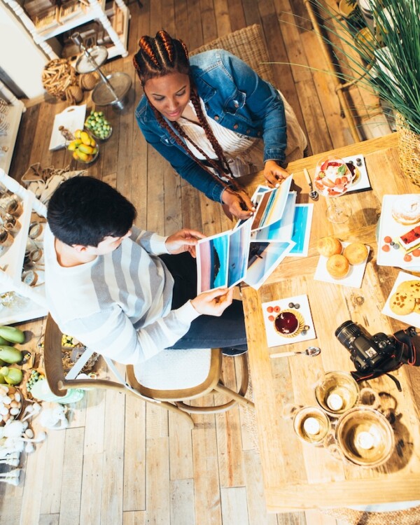 Top view of young mixed race woman and caucasian young man photographers co-working while having a snack at agency